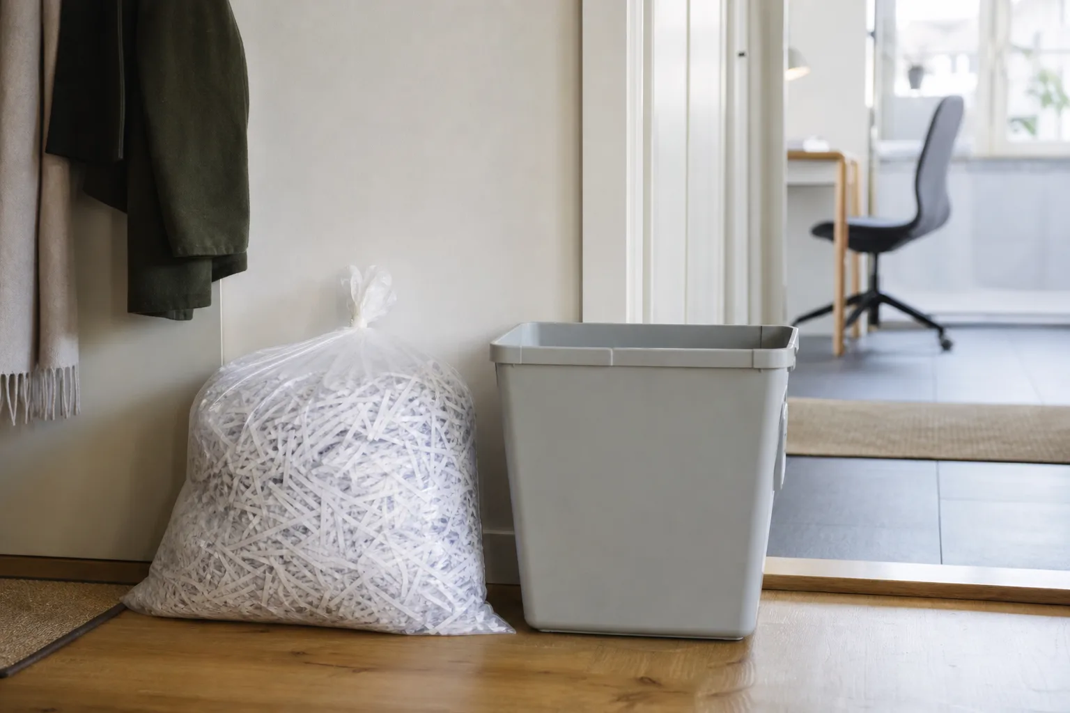 Påse med pappersstrimlor och tömd dokumentförstörarkorg i hall